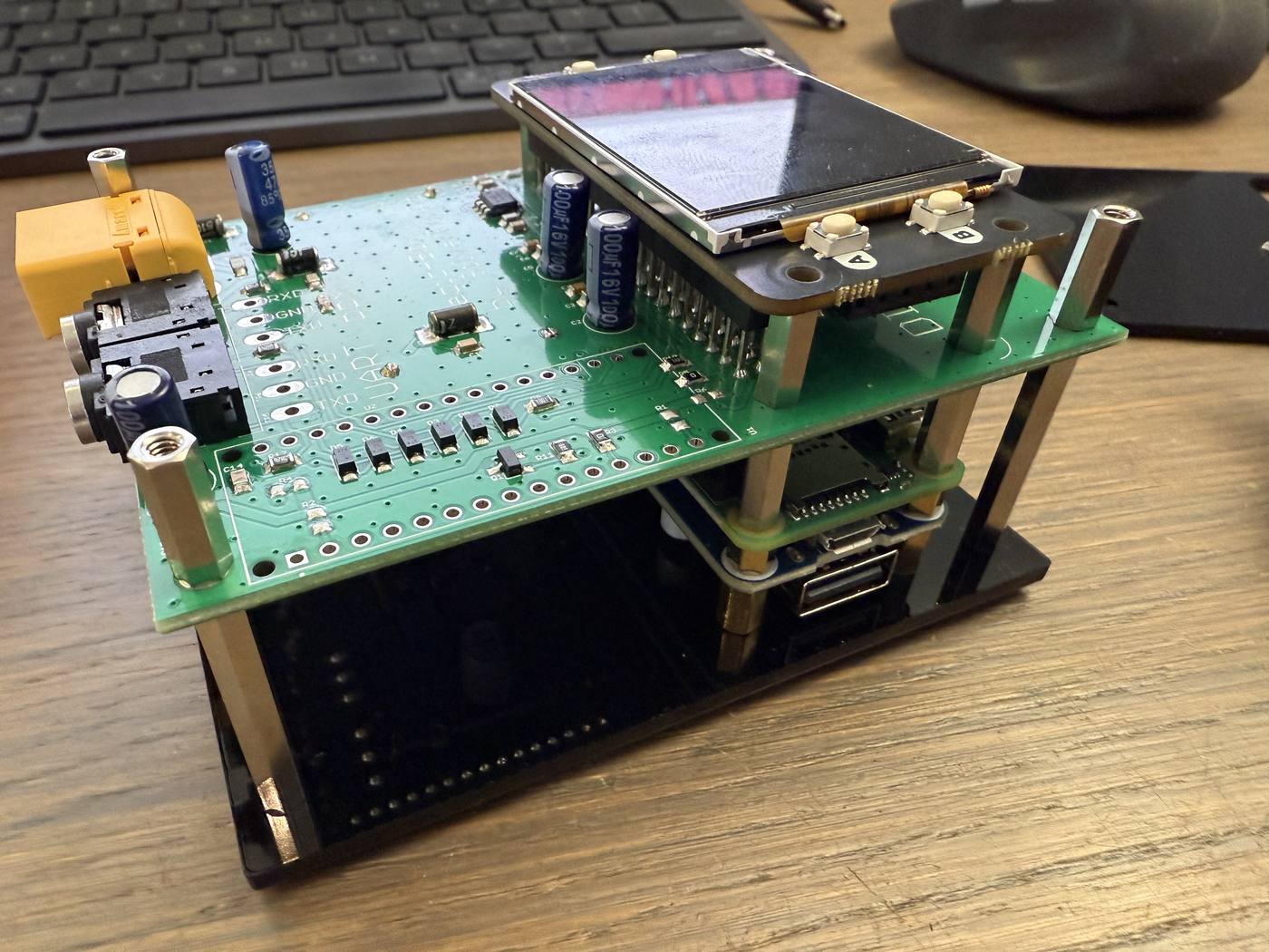 The build part-way through: Raspberry Pi and USB hub at the bottom, mainboard above them on corner posts, screen fitted, the whole stack standing on the base plate