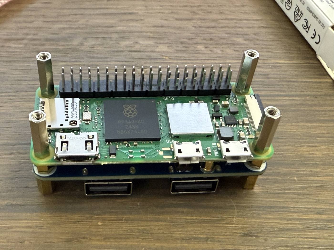 Raspberry Pi Zero 2 W mounted above the USB hub, with four standoffs standing up from its corners